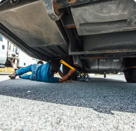 technician under an RV using a floor jack